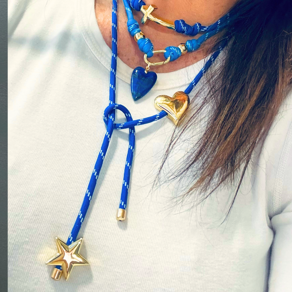 Electric blue paracord wrap necklace designed to tie around the neck, featuring magnetic heart and star charms in 18K gold plating by Julie Saldivia